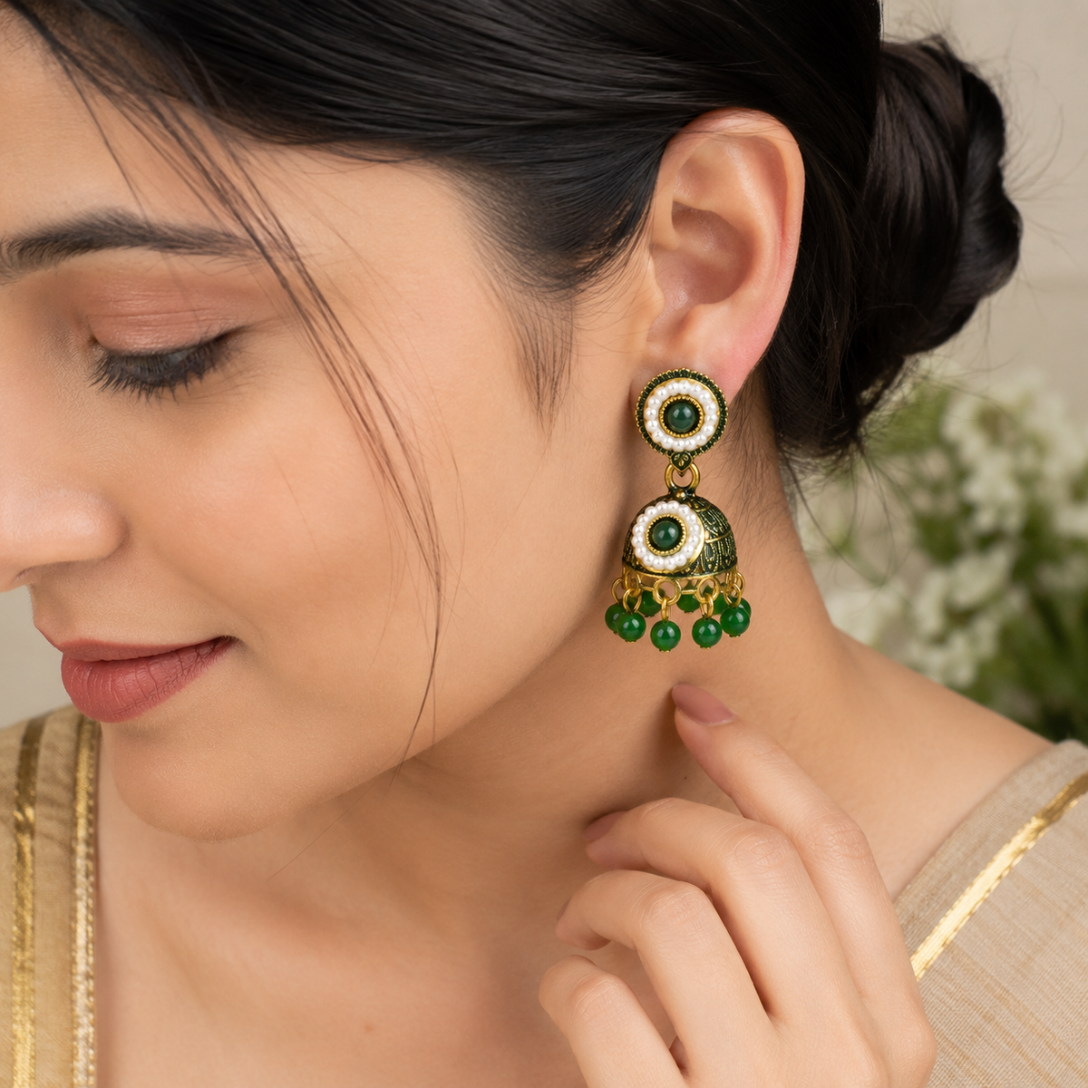 Model wearing green and gold jhumka earring